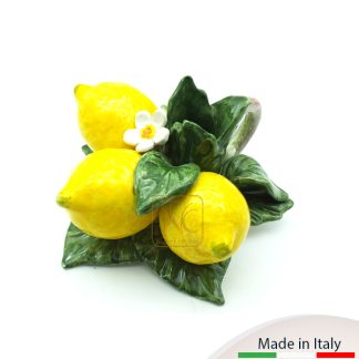 Bugia formata da 3 limoni adagiati su foglie con fiorellino e manico laterale.